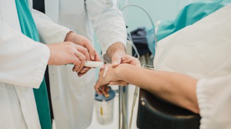 Medical doctor giving patient anesthesia before surgical operation inside modern hospital - Focus on doctor hand holding syringe
